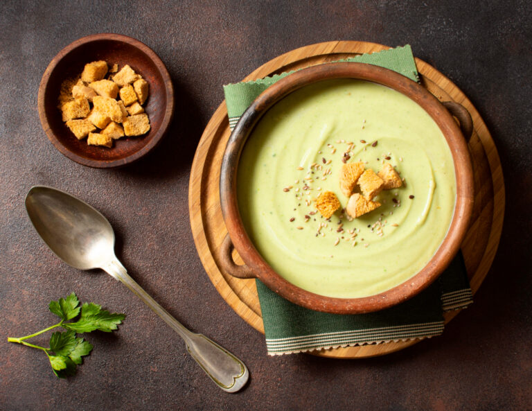 Delicious creamy brown artichoke soup served in a white bowl, garnished with crispy bread croutons.